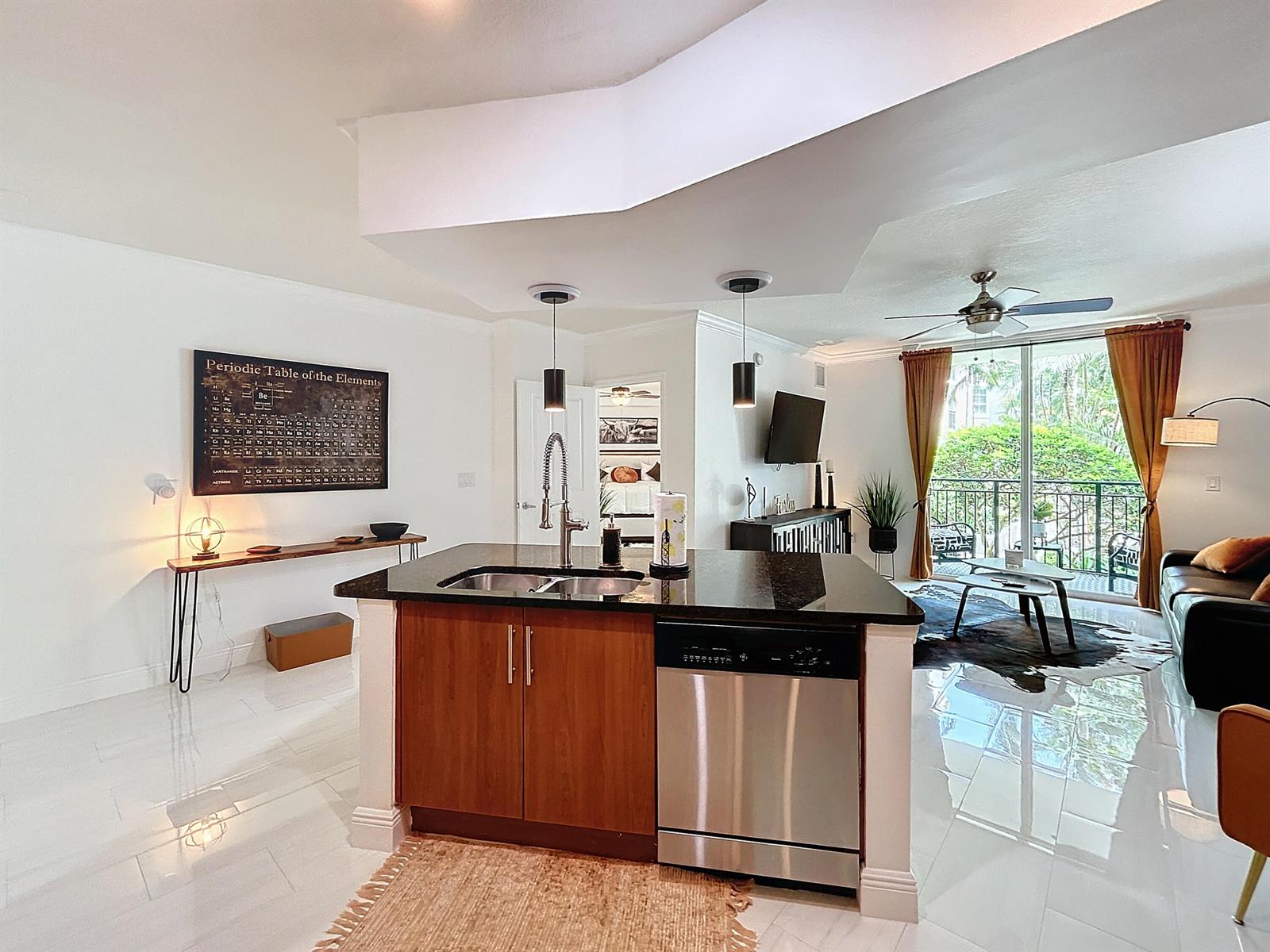 A kitchen island with dark countertops and wood cabinets sits in an open-concept living space — 600 S Dixie Highway # 630, West Palm Beach FL 33401, WEST PALM BEACH, FL