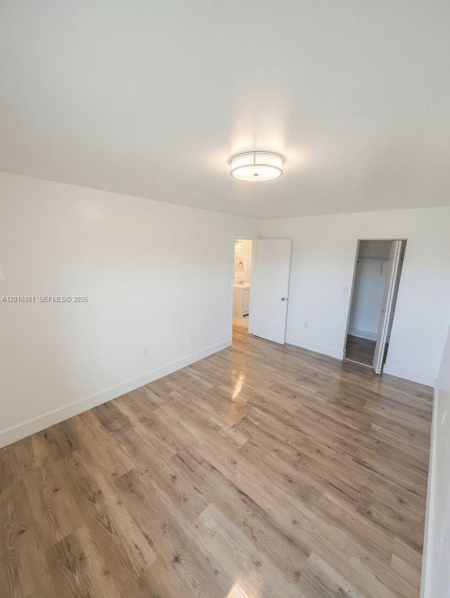 An empty bedroom features light wood-look flooring, white walls, a ceiling light, and two doorways — 6850 W 14th Ct # C28, Hialeah FL 33014, HIALEAH, FL
