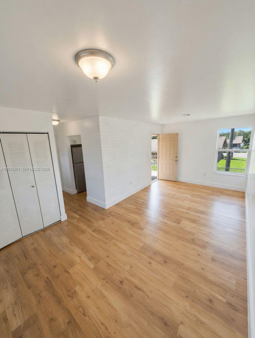 A bright living room features light wood-look flooring, white walls, and a white brick accent wall — 6850 W 14th Ct # C28, Hialeah FL 33014, HIALEAH, FL