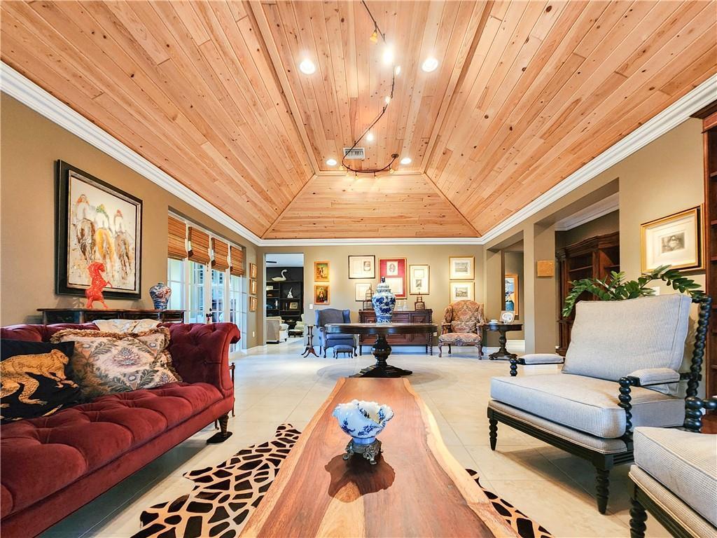 A living room features a vaulted wood-paneled ceiling, a red tufted sofa, and tile flooring — 2815 Saint Barts Square, Vero Beach FL 32967, VERO BEACH, FL