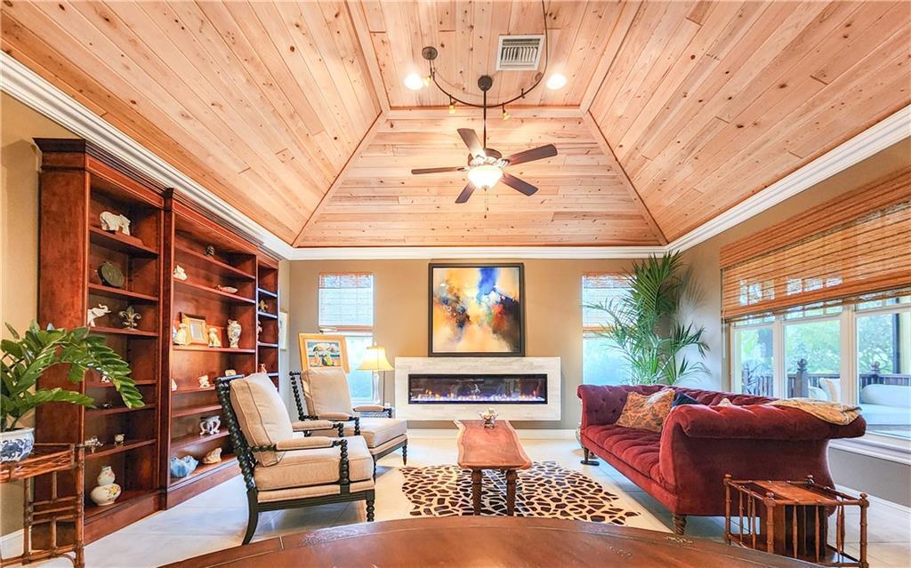 A living room features a wood-paneled tray ceiling, a linear fireplace, and a red sofa — 2815 Saint Barts Square, Vero Beach FL 32967, VERO BEACH, FL