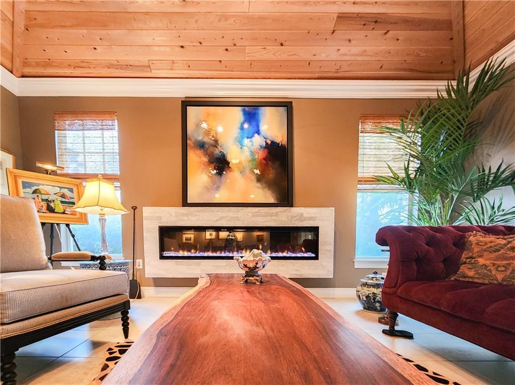A living room features a linear fireplace, wood-plank ceiling, and a large live-edge coffee table — 2815 Saint Barts Square, Vero Beach FL 32967, VERO BEACH, FL
