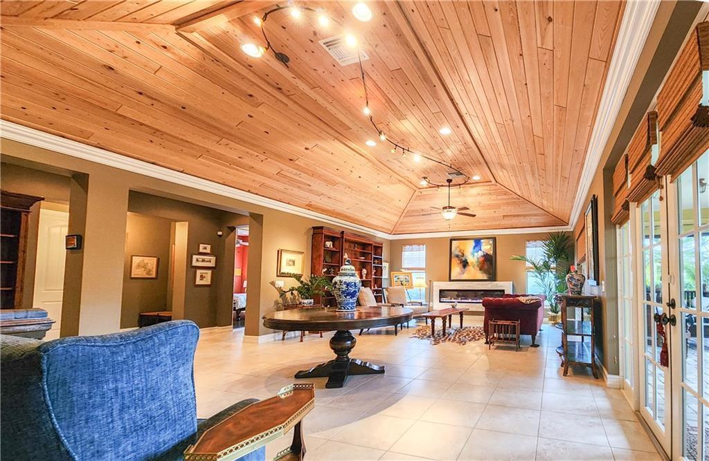 A spacious living room features a vaulted wood-paneled ceiling, tile flooring, and a fireplace — 2815 Saint Barts Square, Vero Beach FL 32967, VERO BEACH, FL