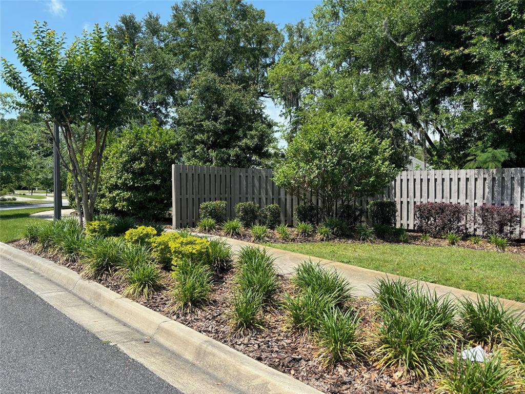 A landscaped garden bed with shrubs and grasses sits in front of a wooden fence — 2148 NW 50TH WAY, GAINESVILLE, FL