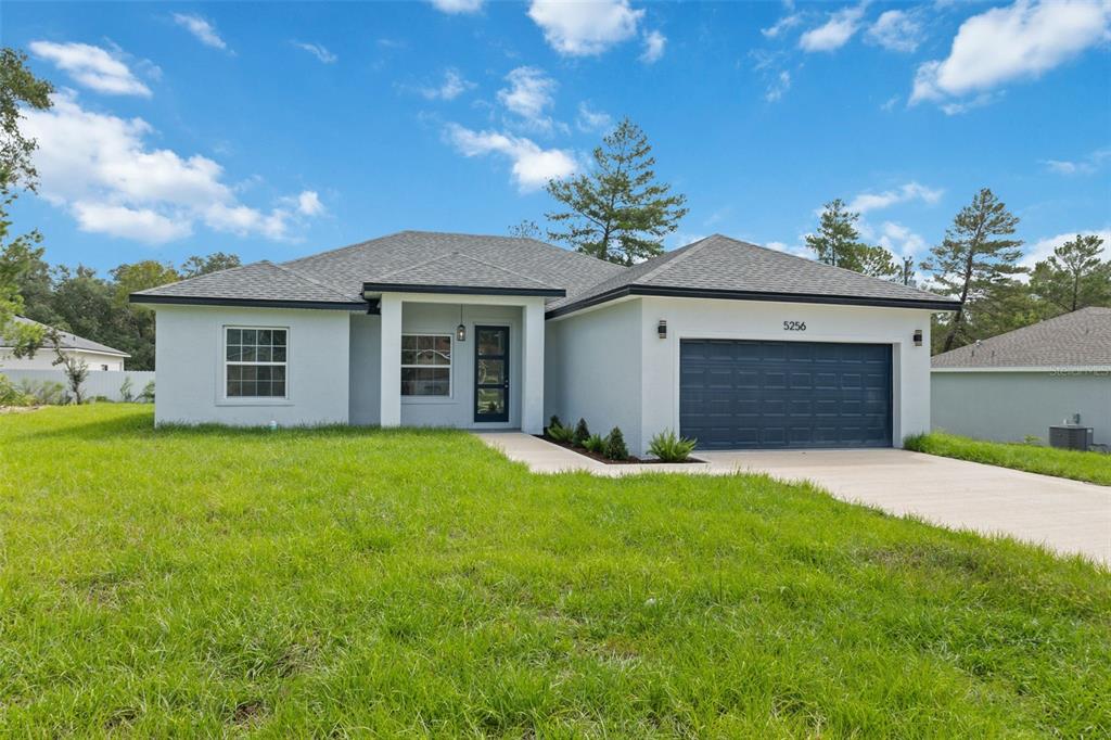 A single-story house with a gray exterior, a dark garage door, and a front walkway — 5256 SW 155TH LOOP, OCALA, FL