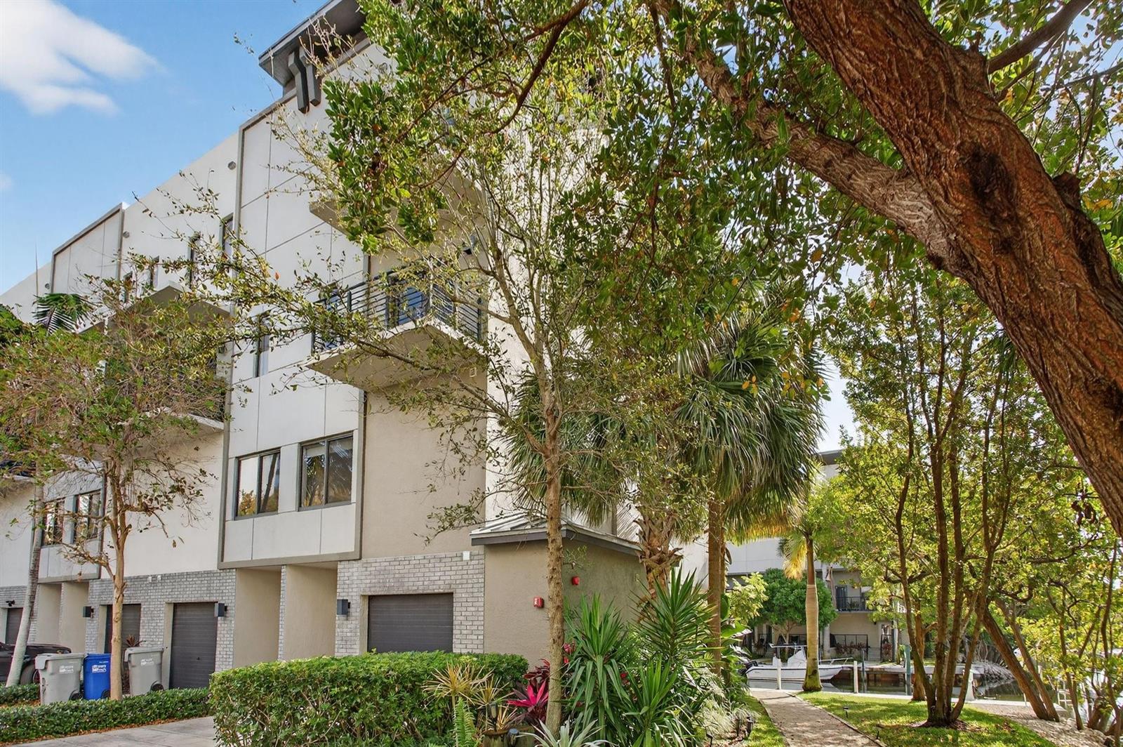 A multi-story modern apartment building with balconies and attached garages sits beside a canal — 196 SE 4th Terrace # 1, Pompano Beach FL 33060, POMPANO BEACH, FL