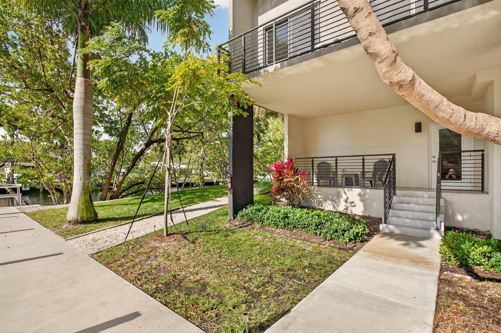 A ground-floor patio with metal railings sits beside a grassy yard and a canal — 196 SE 4th Terrace # 1, Pompano Beach FL 33060, POMPANO BEACH, FL
