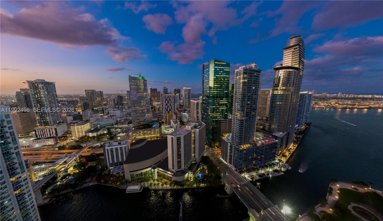 An aerial view of the Miami skyline at dusk featuring skyscrapers and a waterfront bridge — 77 SE 5th St # 2204, Miami FL 33131, MIAMI, FL