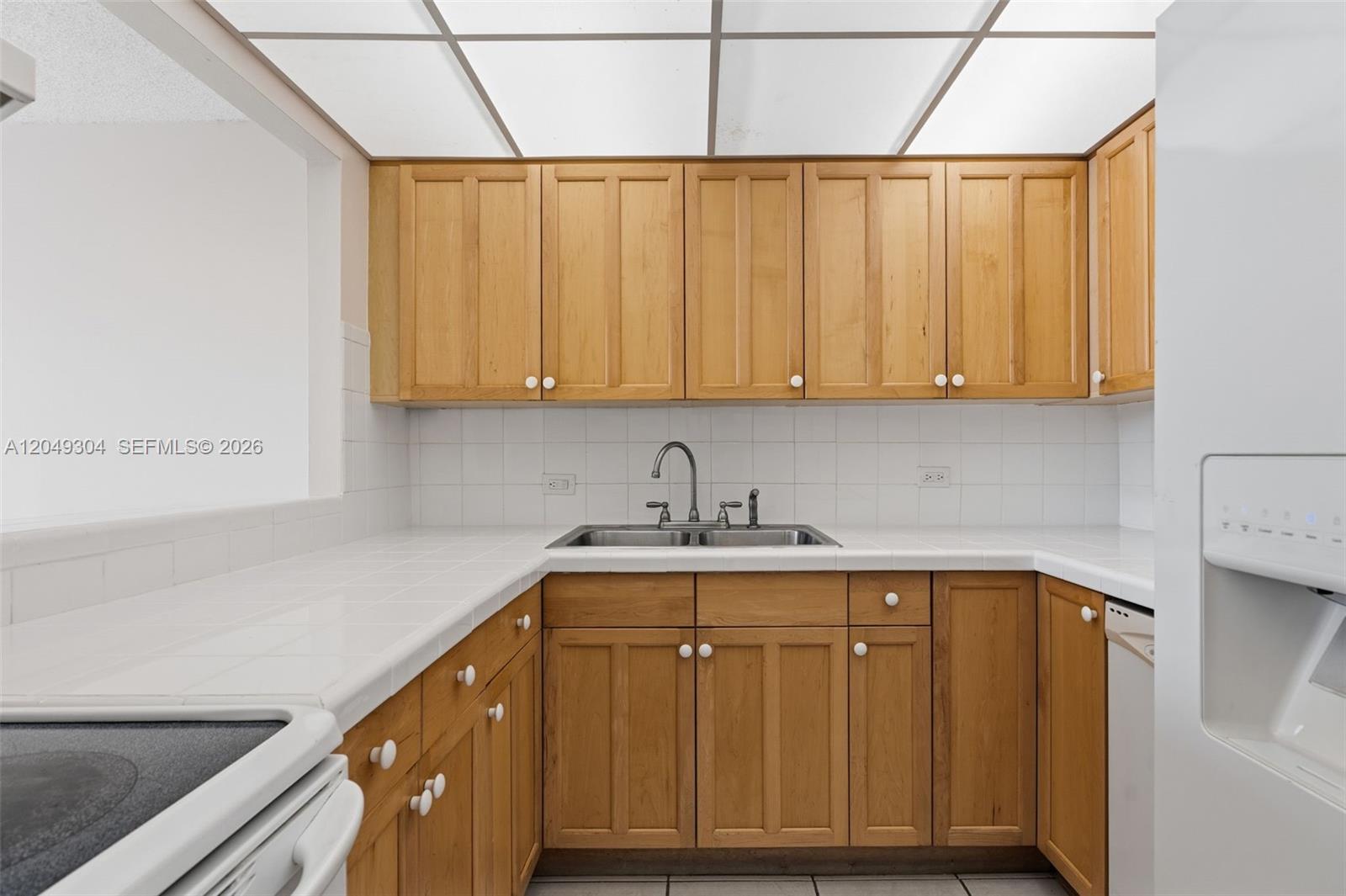 A kitchen features light wood cabinets, white tiled countertops, and a double-basin sink — 10425 SW 112th Ave # 302, Miami FL 33176, MIAMI, FL