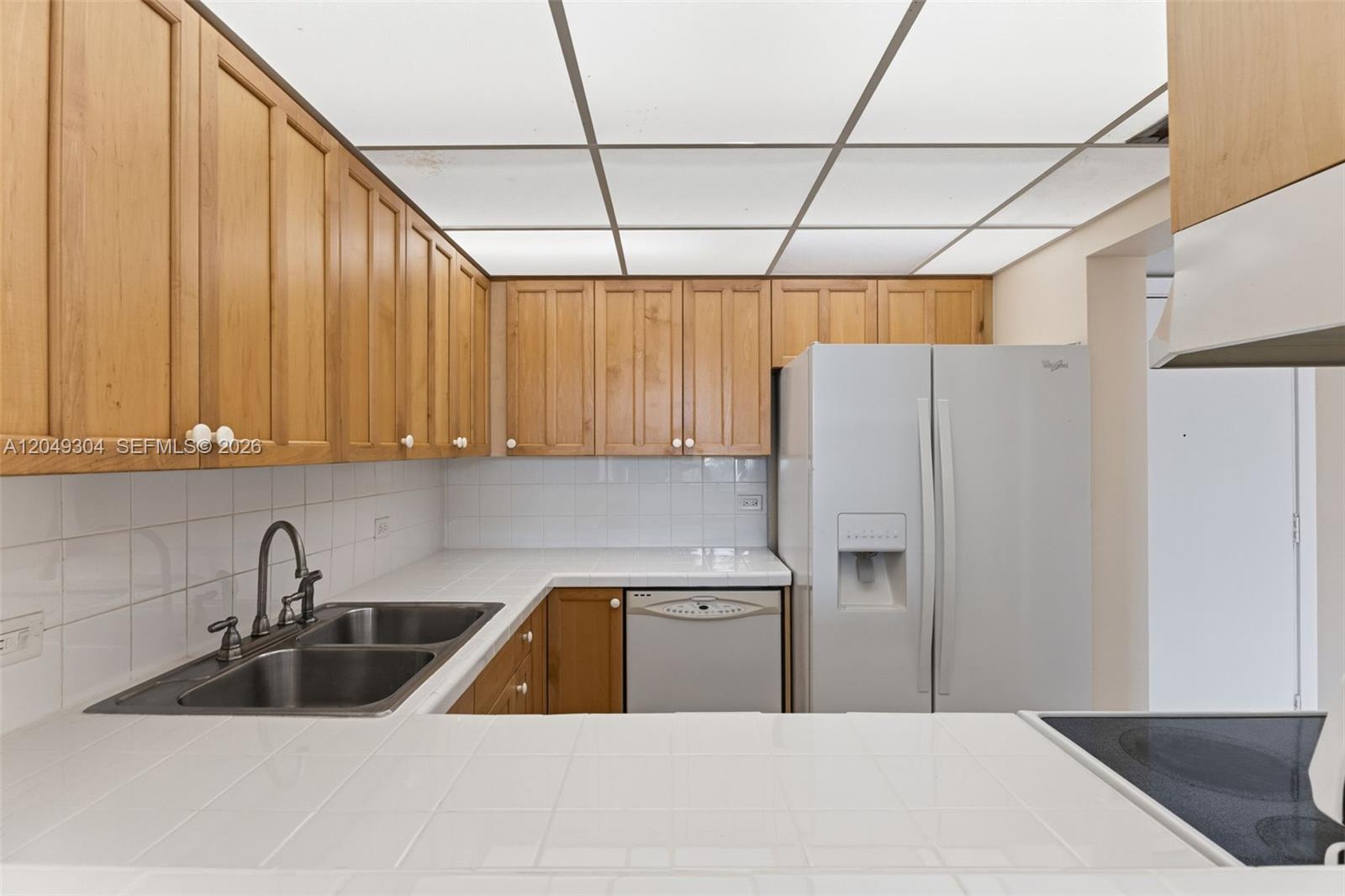A kitchen features light wood cabinets, white tile countertops, a double sink, and a drop ceiling — 10425 SW 112th Ave # 302, Miami FL 33176, MIAMI, FL