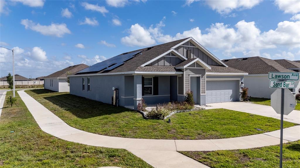A single-story house with a gray exterior, solar panels, and a two-car garage — 401 SANDBAR LN, HAINES CITY, FL