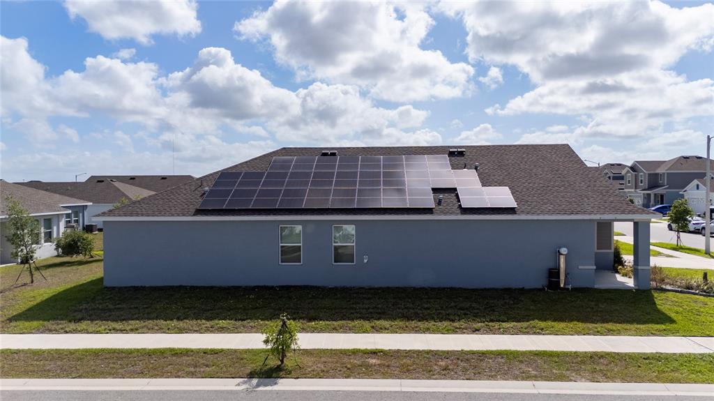 An exterior view of a single-story house featuring a large solar panel array on the roof — 401 SANDBAR LN, HAINES CITY, FL