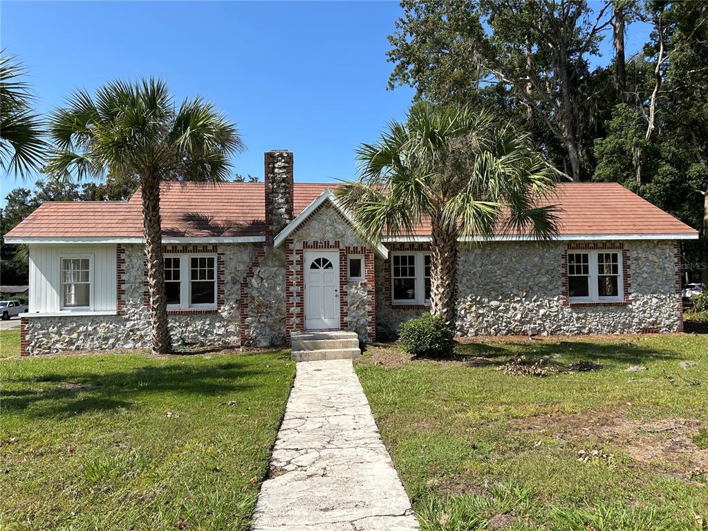 A stone-faced house with a red shingled roof and two palm trees in the front yard — 1008 NW 13TH STREET, GAINESVILLE, FL