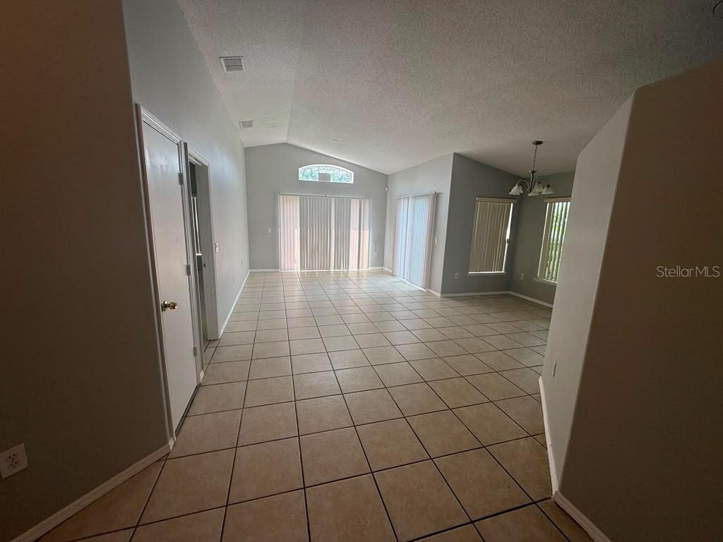 An open-concept living area with vaulted ceilings, tile flooring, and sliding glass doors — 1440 TIMBERBEND CIRCLE, ORLANDO, FL