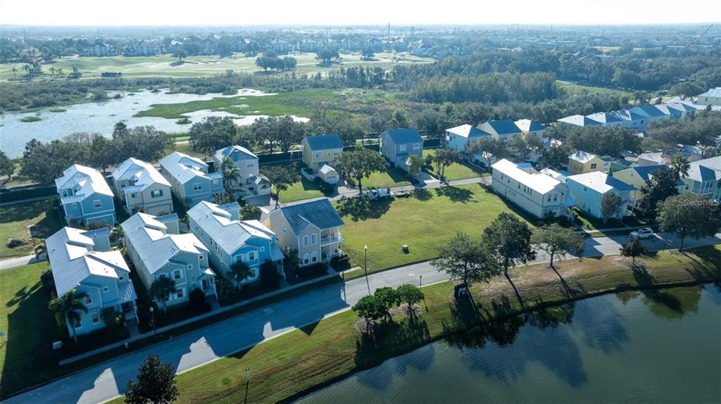 An aerial view shows a neighborhood of light-colored houses situated near a lake and wetlands — 1523 FAIRVIEW CIRCLE, KISSIMMEE, FL