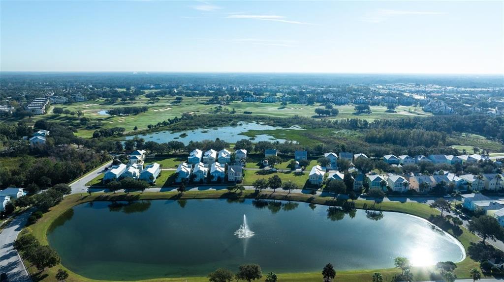 An aerial view shows a residential neighborhood with a large pond and fountain — 1523 FAIRVIEW CIRCLE, KISSIMMEE, FL