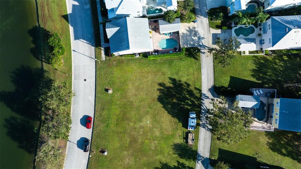 An aerial view shows a vacant residential lot situated between two paved roads and water — 1523 FAIRVIEW CIRCLE, KISSIMMEE, FL