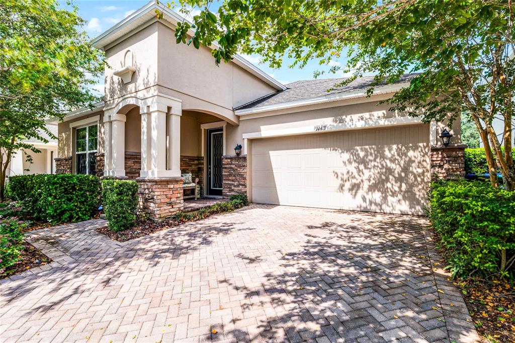 A single-story house with a beige stucco facade, stone accents, and a paved driveway — 14413 MAGNOLIA RIDGE LOOP, WINTER GARDEN, FL