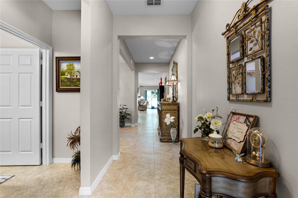 A tiled hallway leads from a foyer with a console table toward a living area — 14413 MAGNOLIA RIDGE LOOP, WINTER GARDEN, FL