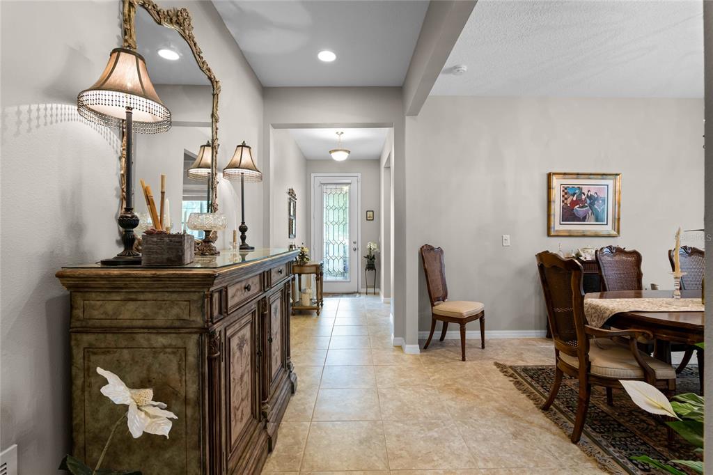 A dining room and entryway feature tile flooring, a decorative sideboard, and a glass-paneled door — 14413 MAGNOLIA RIDGE LOOP, WINTER GARDEN, FL