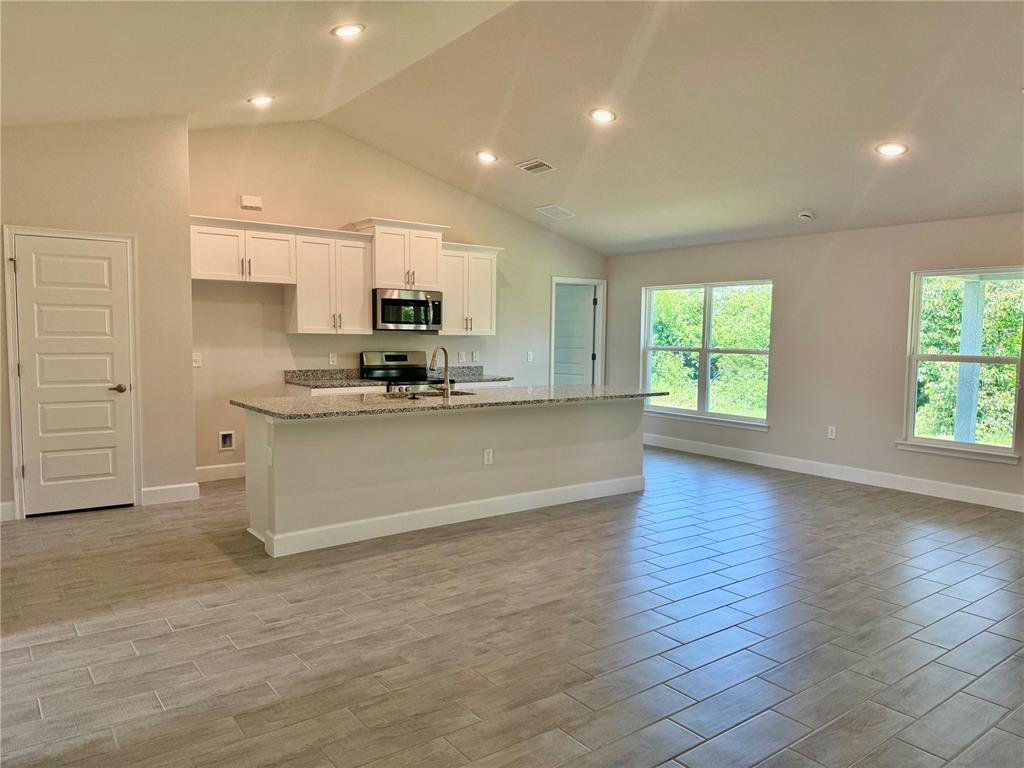 A kitchen with white cabinets, granite countertops, and a center island in an open-concept room — 9590 LITTLE ROCK STREET, PORT CHARLOTTE, FL