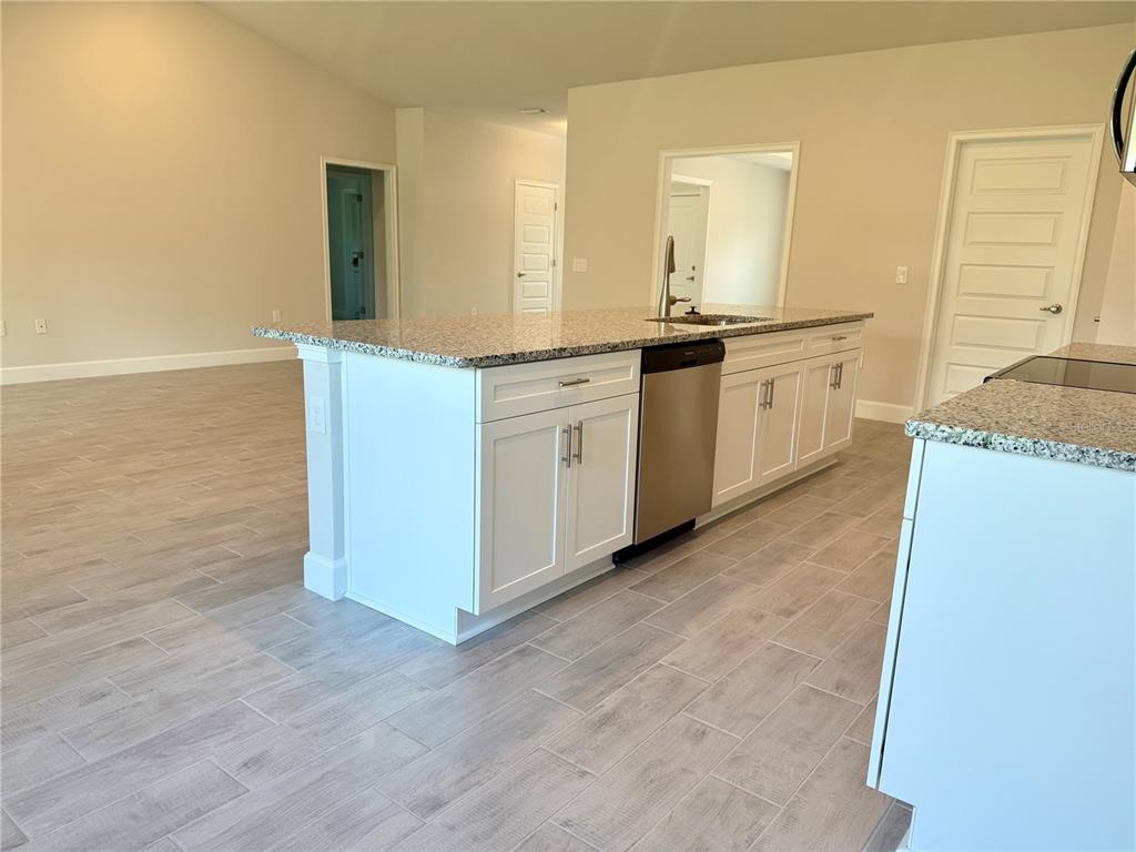 A kitchen island with white cabinets and granite countertops sits on a light-colored tiled floor — 9590 LITTLE ROCK STREET, PORT CHARLOTTE, FL