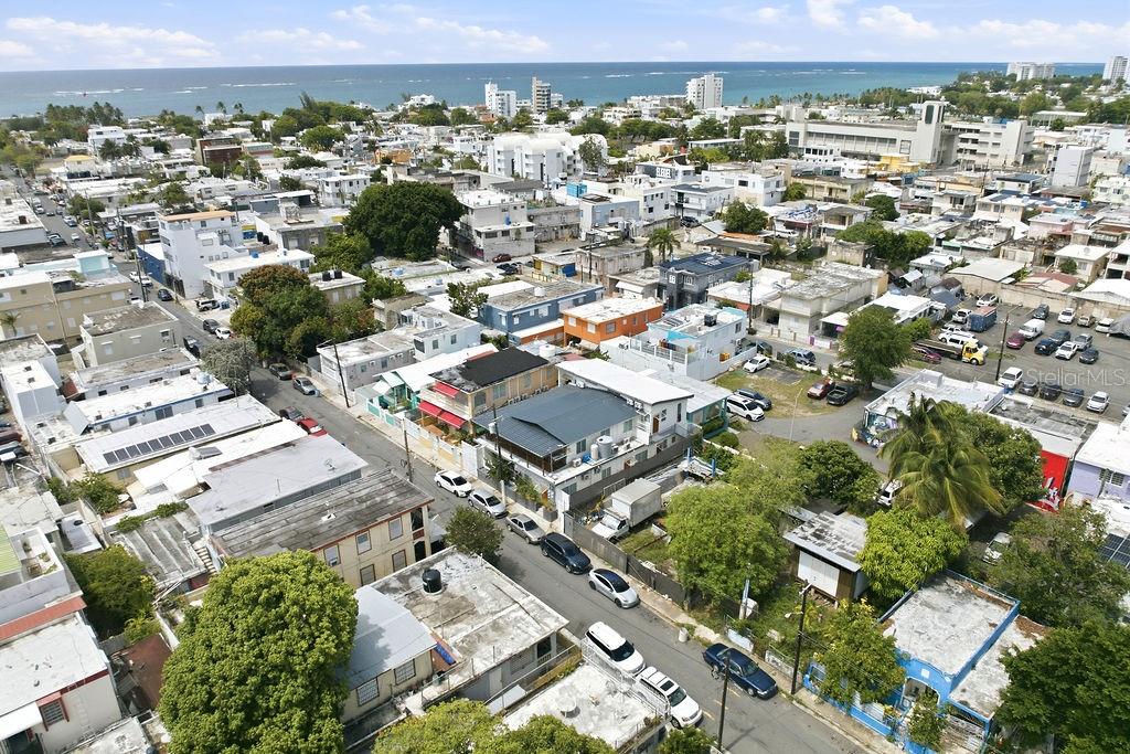 An aerial view shows a dense urban neighborhood with many flat-roofed buildings near the coast — 119 SANTA CECILIA, SAN JUAN, PR