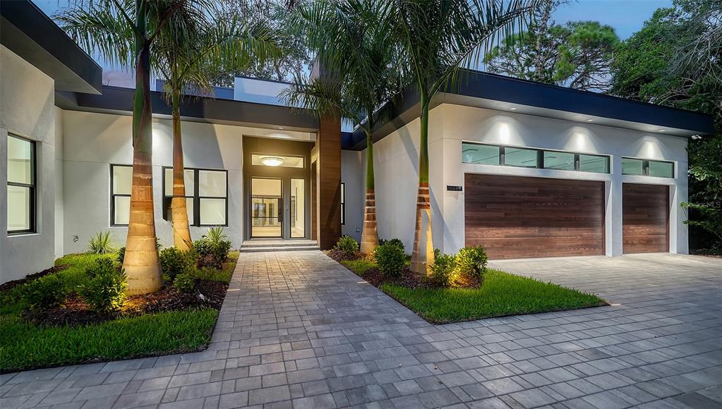 A modern house exterior features a paved walkway, palm trees, and a three-car garage — 1429 N LAKE SHORE DRIVE, SARASOTA, FL