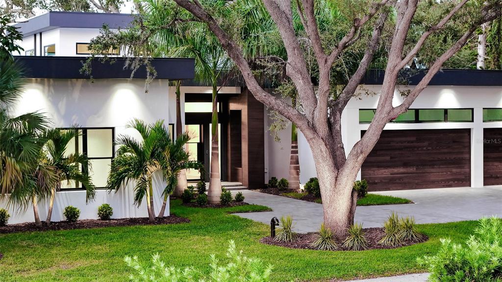 A modern white house with a dark wood garage door and palm trees in the yard — 1429 N LAKE SHORE DRIVE, SARASOTA, FL