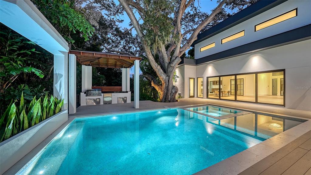 A modern house exterior features a swimming pool, a covered outdoor kitchen, and a large tree — 1429 N LAKE SHORE DRIVE, SARASOTA, FL