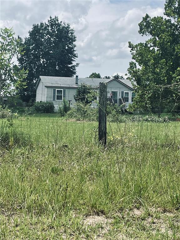 A light-colored single-story house sits behind a wire fence in a grassy field — 16570 SW 58TH LANE, OCALA, FL