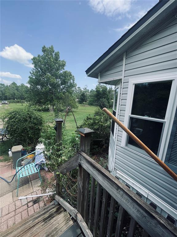 A wooden staircase leads down from a light blue house to a paved patio area — 16570 SW 58TH LANE, OCALA, FL