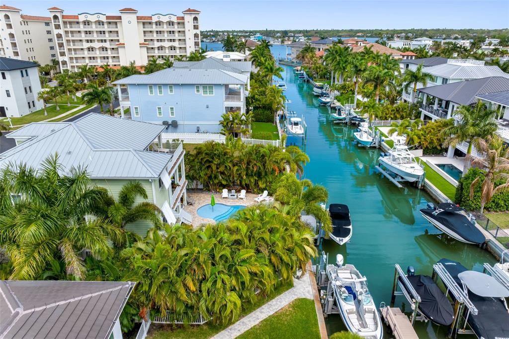 An aerial view shows a canal lined with houses, private docks, boats, and palm trees — 124 FOREST HILLS DRIVE, REDINGTON SHORES, FL
