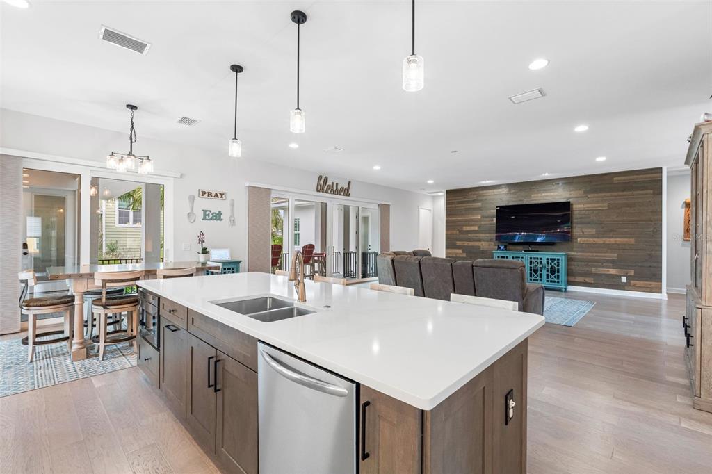 A modern open-concept kitchen features a large white island, wood cabinetry, and a living area — 124 FOREST HILLS DRIVE, REDINGTON SHORES, FL
