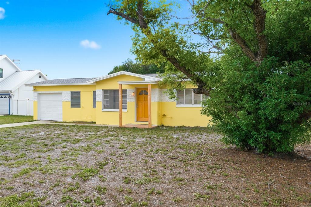 A yellow single-story house with a white garage door and a large tree in front — 4325 S COOLIDGE AVENUE, TAMPA, FL
