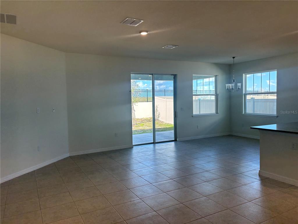 An open-concept living area features tile flooring, a sliding glass door, and a dining space — 2355 SELENIA STREET, LAKE ALFRED, FL