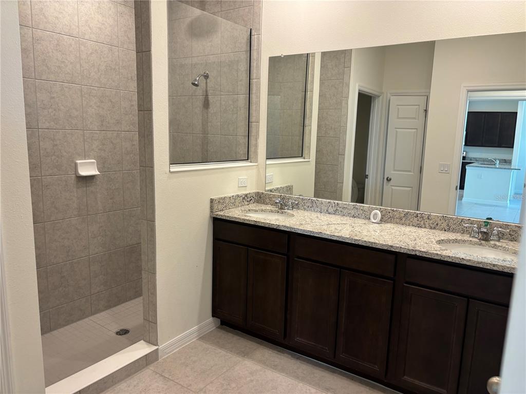 A bathroom features a tiled walk-in shower, a double-sink granite vanity, and dark wood cabinets — 2355 SELENIA STREET, LAKE ALFRED, FL