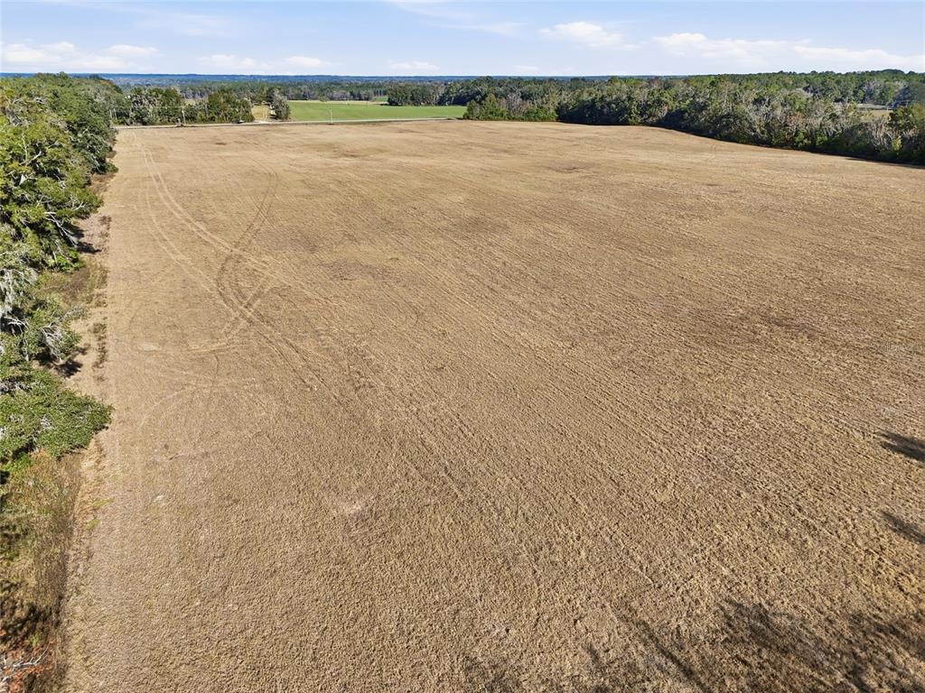 An aerial view shows a large, flat, harvested agricultural field bordered by trees — Hwy 236 NW 236, ALACHUA, FL