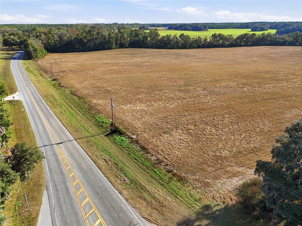 An aerial view shows a paved road bordering a large, open, dry grassy field — Hwy 236 NW 236, ALACHUA, FL