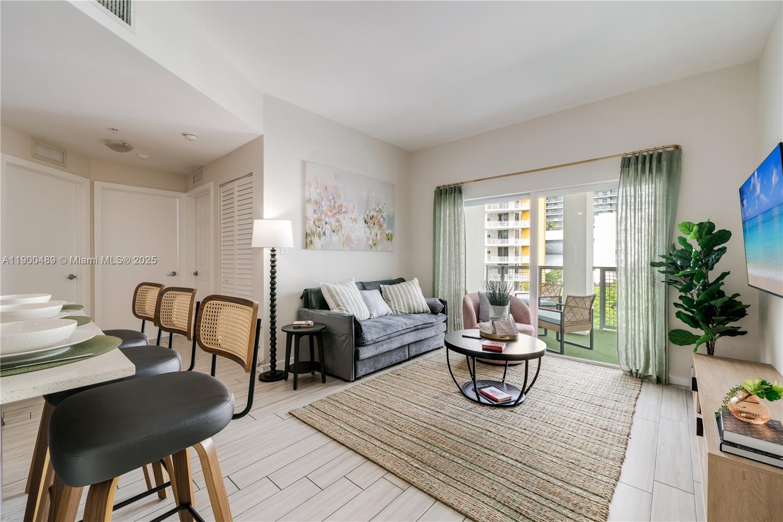 A living room features a grey sofa, a round coffee table, and a balcony view — 481 NE 29th St # 601, Miami FL 33137, MIAMI, FL