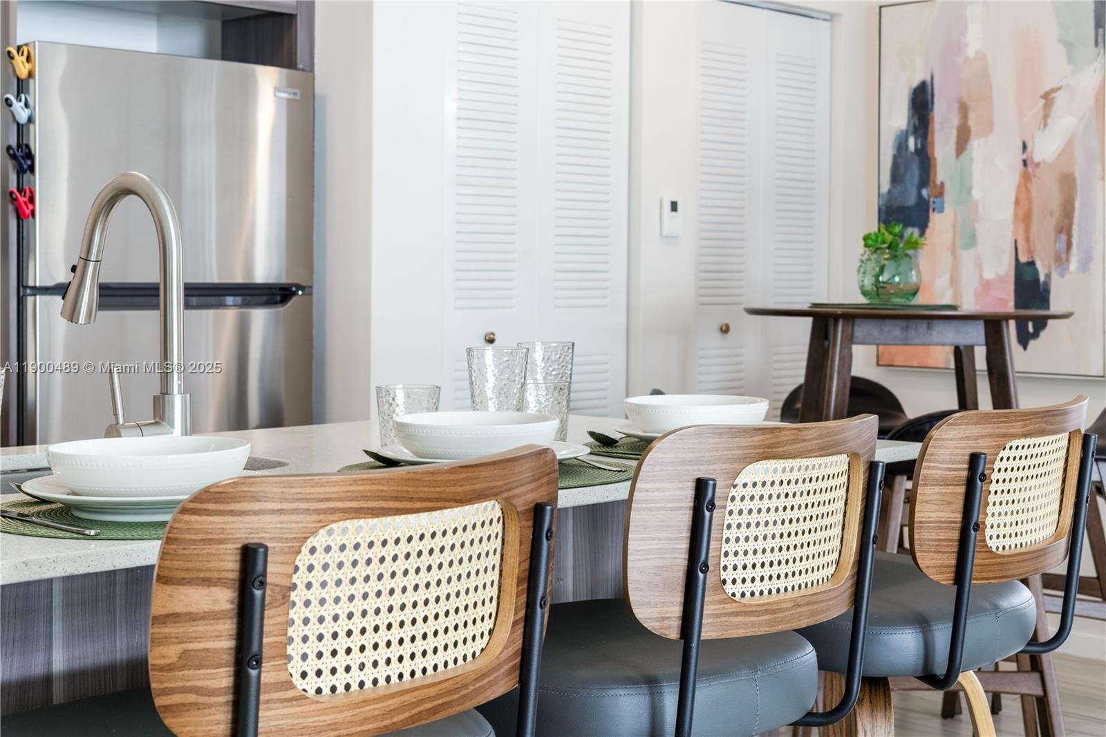 A kitchen island with three cane-back chairs sits in front of a stainless steel refrigerator — 481 NE 29th St # 601, Miami FL 33137, MIAMI, FL