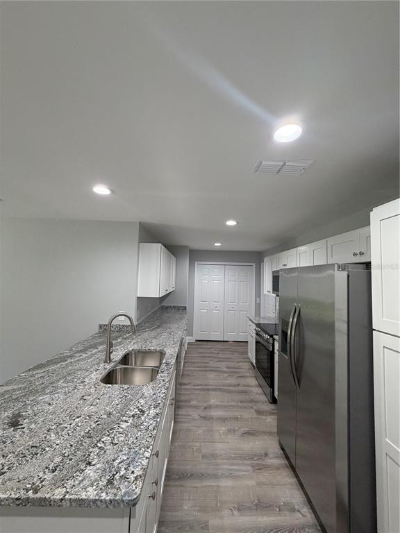 A kitchen features granite countertops, stainless steel appliances, white cabinets, and wood-look flooring — 1981 LEMON DRIVE, LAKE WALES, FL