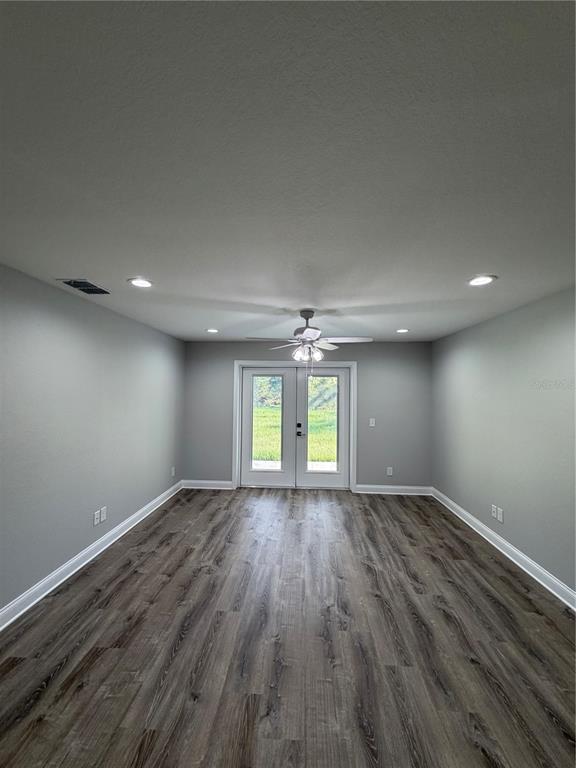 An empty room with gray walls, wood-look flooring, a ceiling fan, and glass double doors — 1981 LEMON DRIVE, LAKE WALES, FL