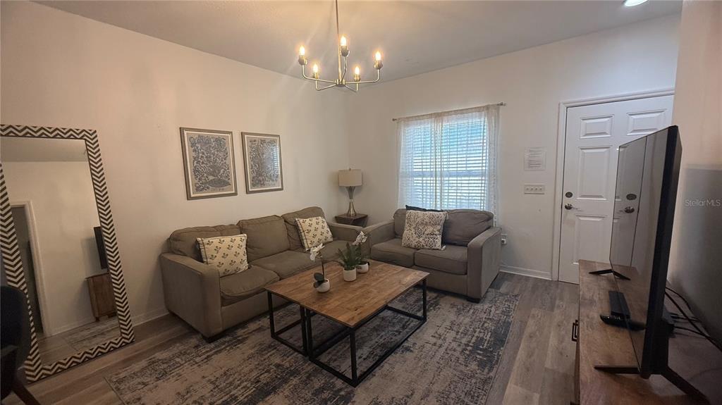 A living room features a sofa, loveseat, coffee table, area rug, and a large mirror — 8919 SHINE DRIVE, KISSIMMEE, FL