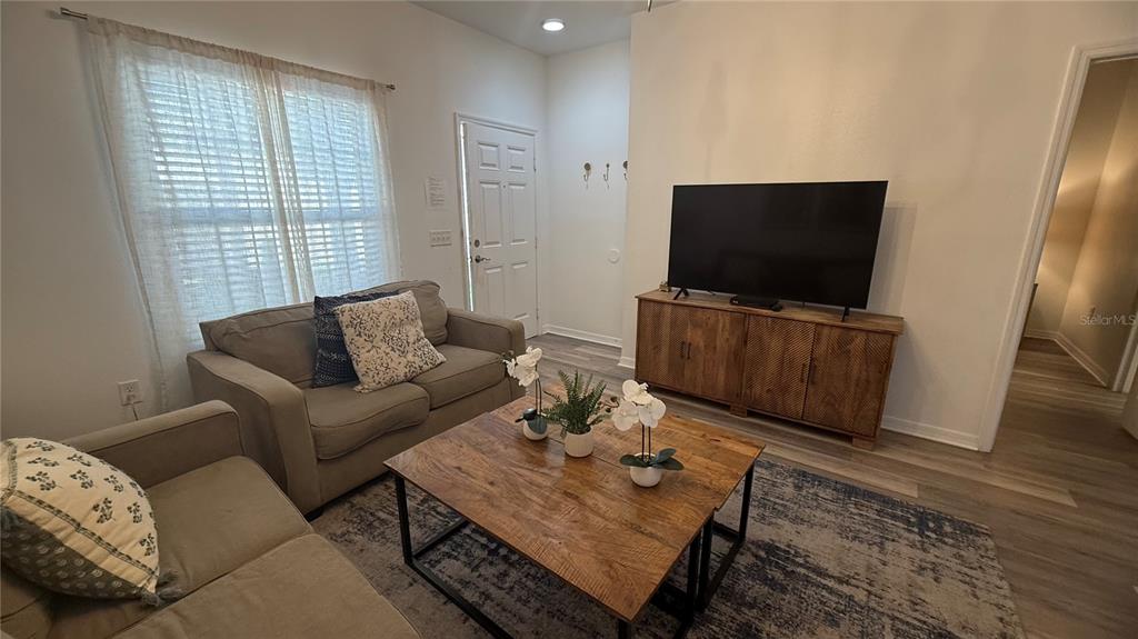 A living room features a sofa, a wooden coffee table, and a television on a console — 8919 SHINE DRIVE, KISSIMMEE, FL