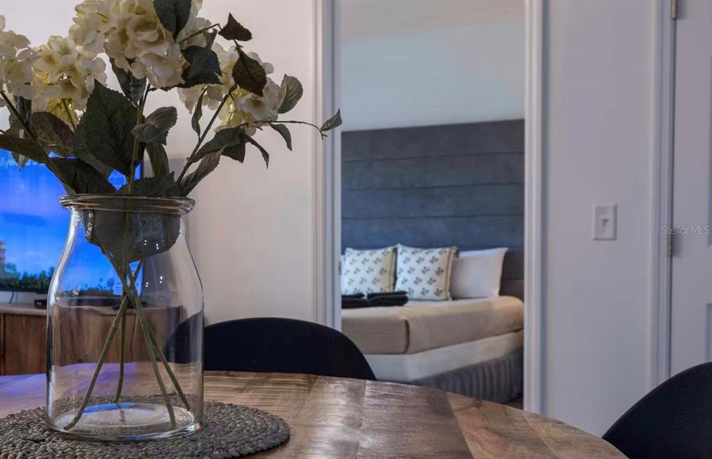 A glass vase with white flowers sits on a wooden table before a bedroom — 8919 SHINE DRIVE, KISSIMMEE, FL