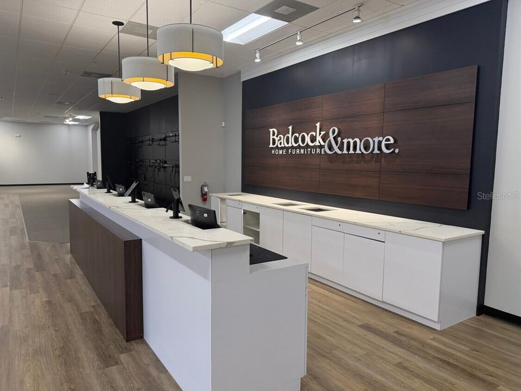 A commercial reception desk with white cabinets and a wood-paneled wall featuring store branding — 311 S RIDGEWOOD AVENUE, EDGEWATER, FL