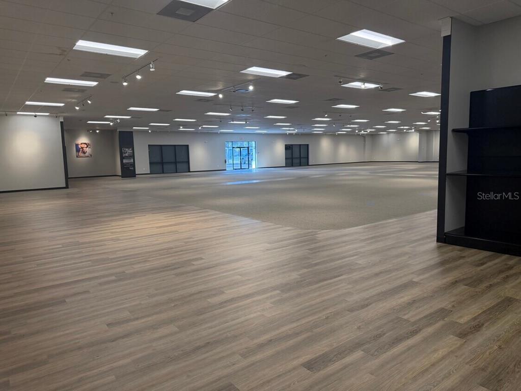 A large, open commercial space features wood-look flooring, carpeted areas, and recessed ceiling lighting — 311 S RIDGEWOOD AVENUE, EDGEWATER, FL