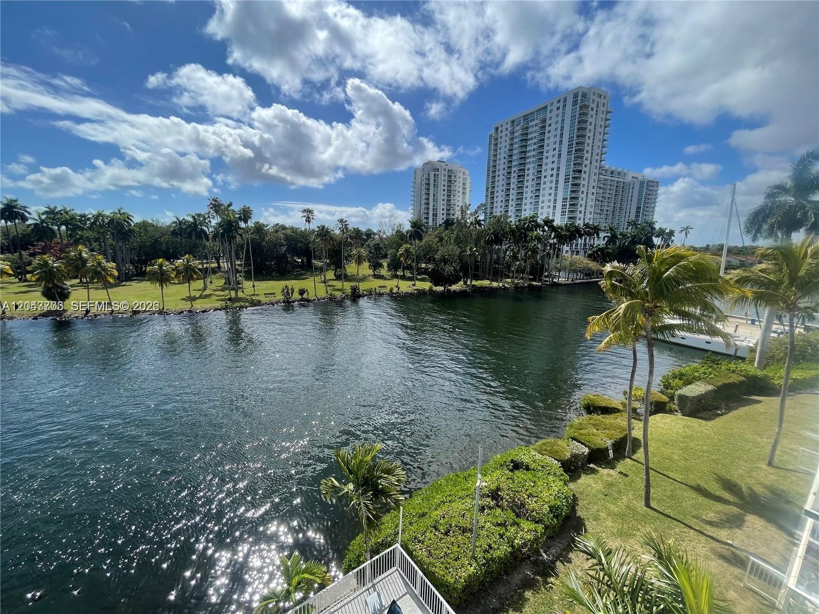 An elevated view of a canal with palm trees, manicured lawns, and high-rise buildings — 1740 NW N River Dr # 517, Miami FL 33125, MIAMI, FL