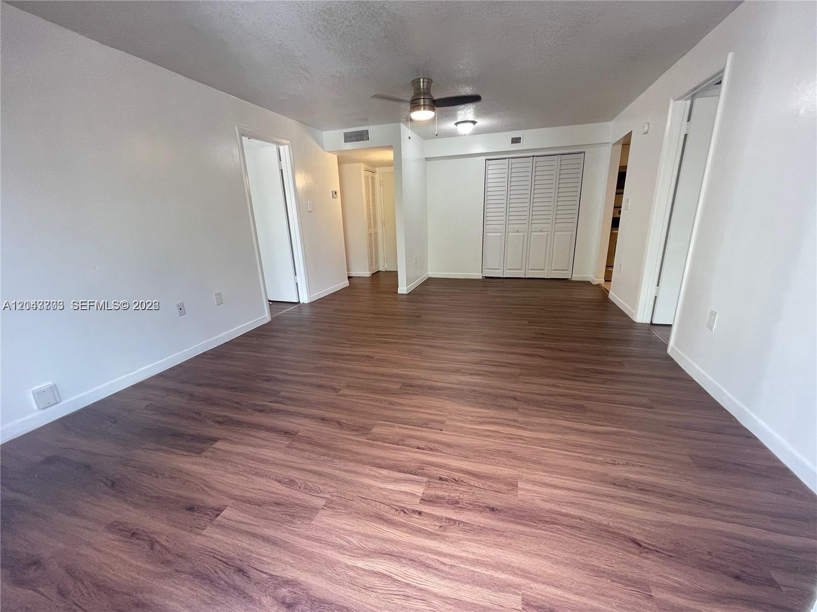 An empty room features wood-look flooring, white walls, a ceiling fan, and louvered closet doors — 1740 NW N River Dr # 517, Miami FL 33125, MIAMI, FL